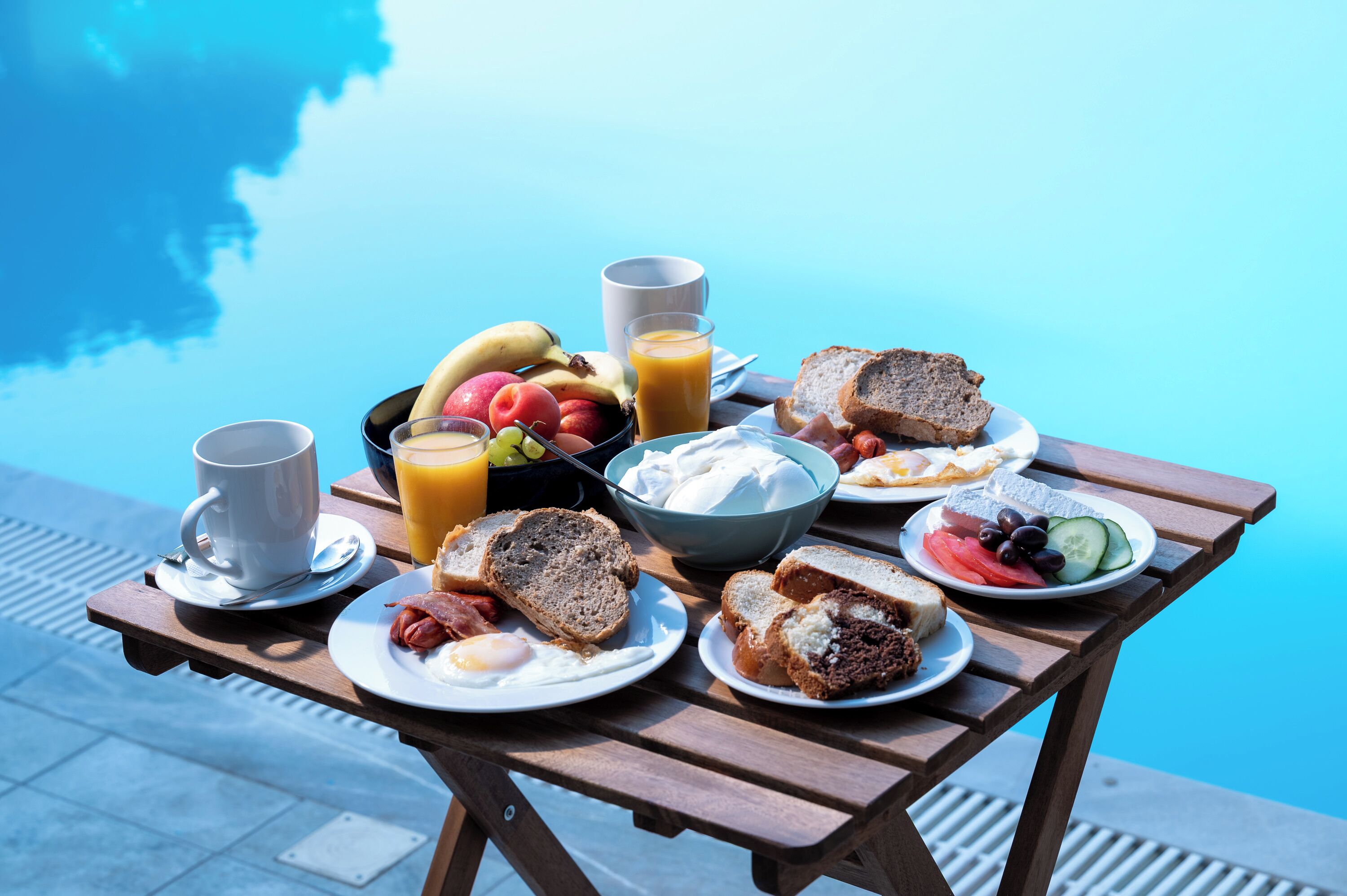 A breakfast table with various food items and a glass of orange juice.