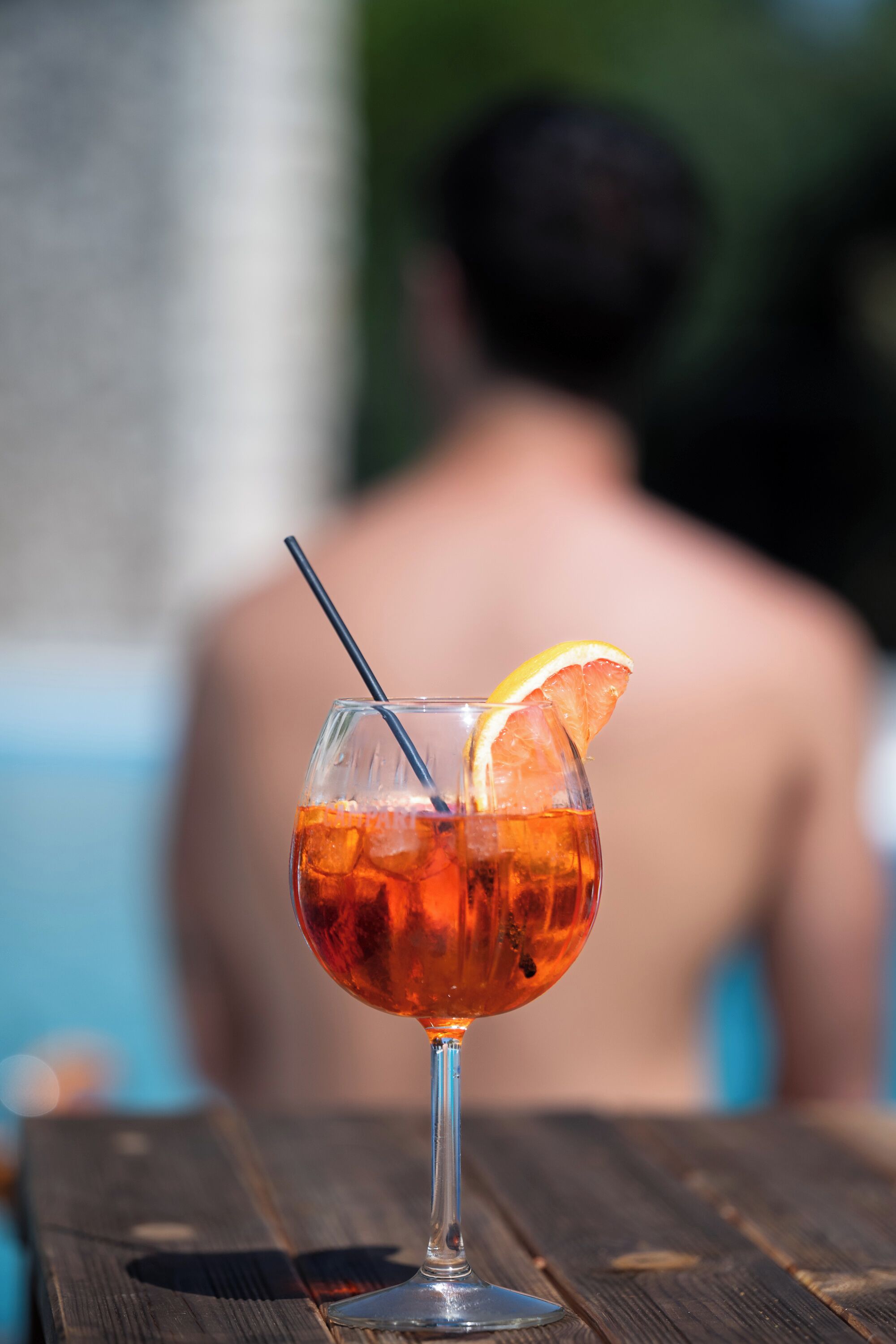 A cocktail glass with an orange slice garnish on a wooden table.