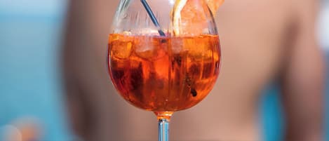 A cocktail glass with an orange slice garnish on a wooden table.