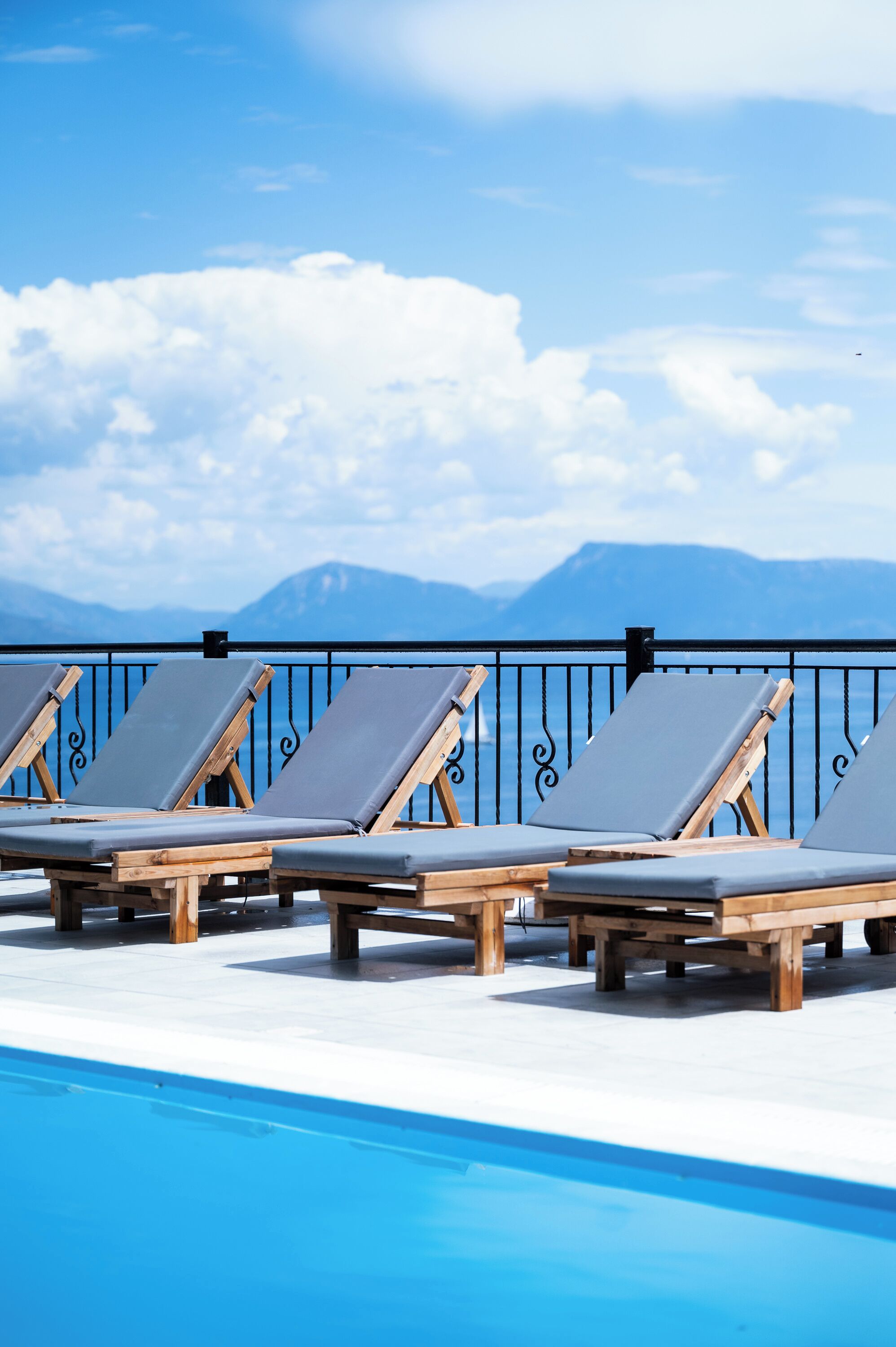 A poolside area with lounge chairs and a view of mountains.