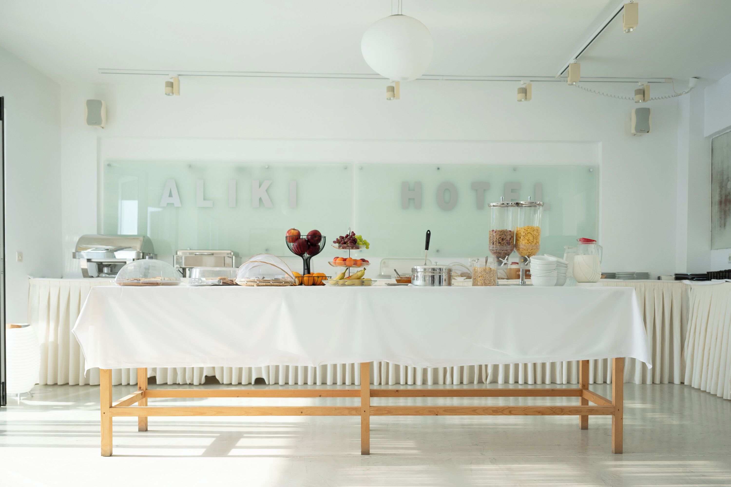 A buffet table with various food items and a glass display case in a bright, modern hotel setting.