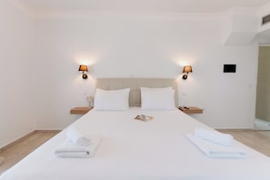 A hotel room with a large bed, two bedside tables, and wall-mounted lamps. - Aliki Hotel (Lefkada)