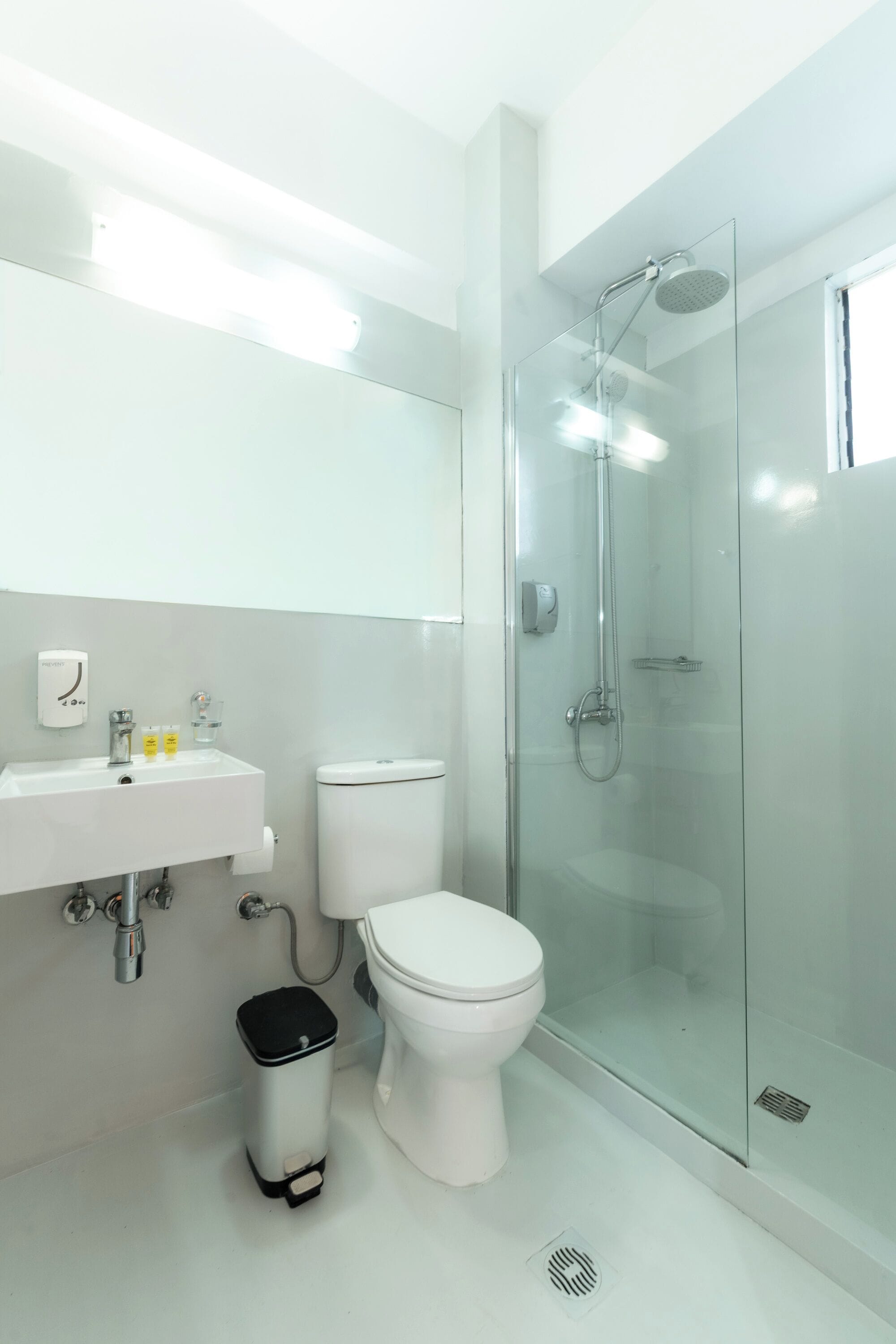 A modern bathroom with a glass-enclosed shower, a white sink, and a toilet.