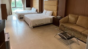 Habitación de hotel con dos camas, un sofá, un televisor y una ventana con cortinas.