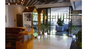Een receptie met een houten balie, plantenbakken en een zithoek met een blauwe bank.