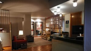 Un vaste espace de vie doté d’un plancher en bois, d’un canapé, d’un fauteuil rouge et d’une table basse. Il y a également un coin cuisine avec un réfrigérateur et un four à micro-ondes.