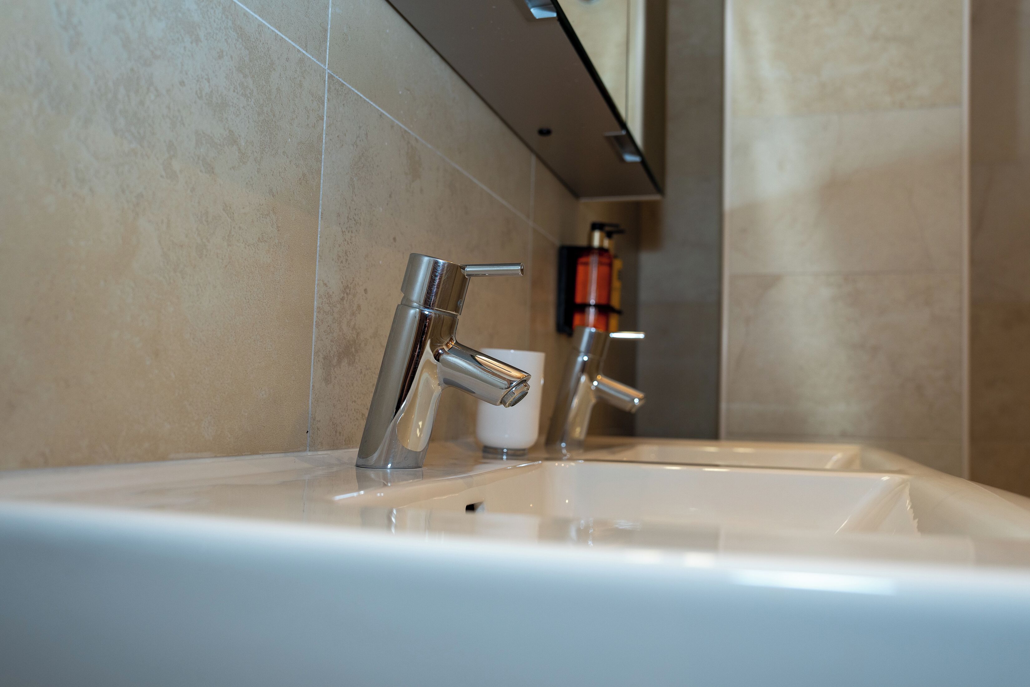 Un baño con un lavamanos moderno y dos grifos.