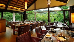 A dining area with wooden tables and chairs, large windows with a view of lush greenery. - Mudanwan Villa (Mudan)