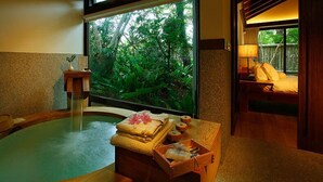 A spa room with a hot tub, a wooden bench with towels, and a window with a view of greenery. - Mudanwan Villa (Mudan)