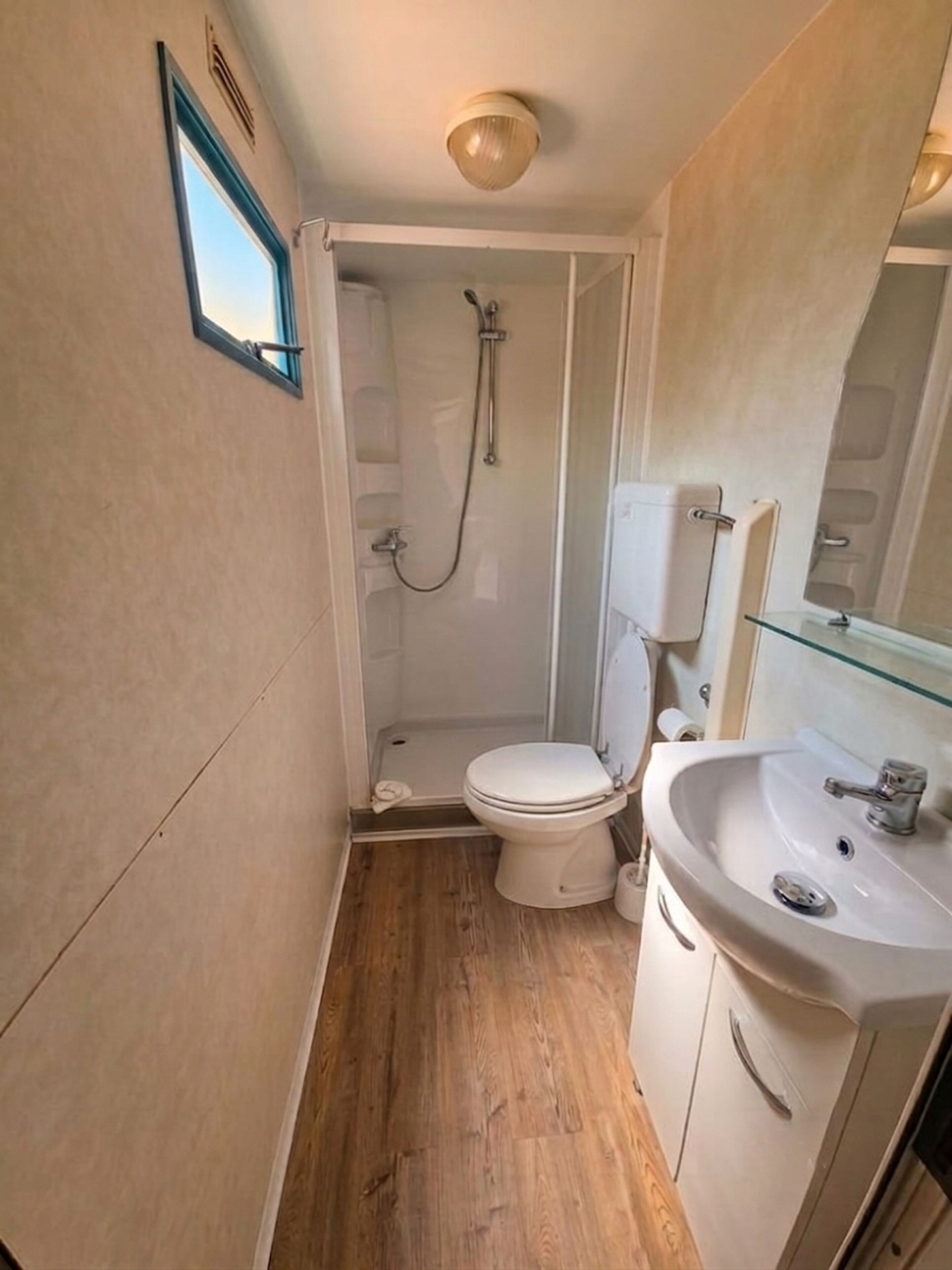 Ein kleines Badezimmer mit Dusche, Toilette und Waschbecken.