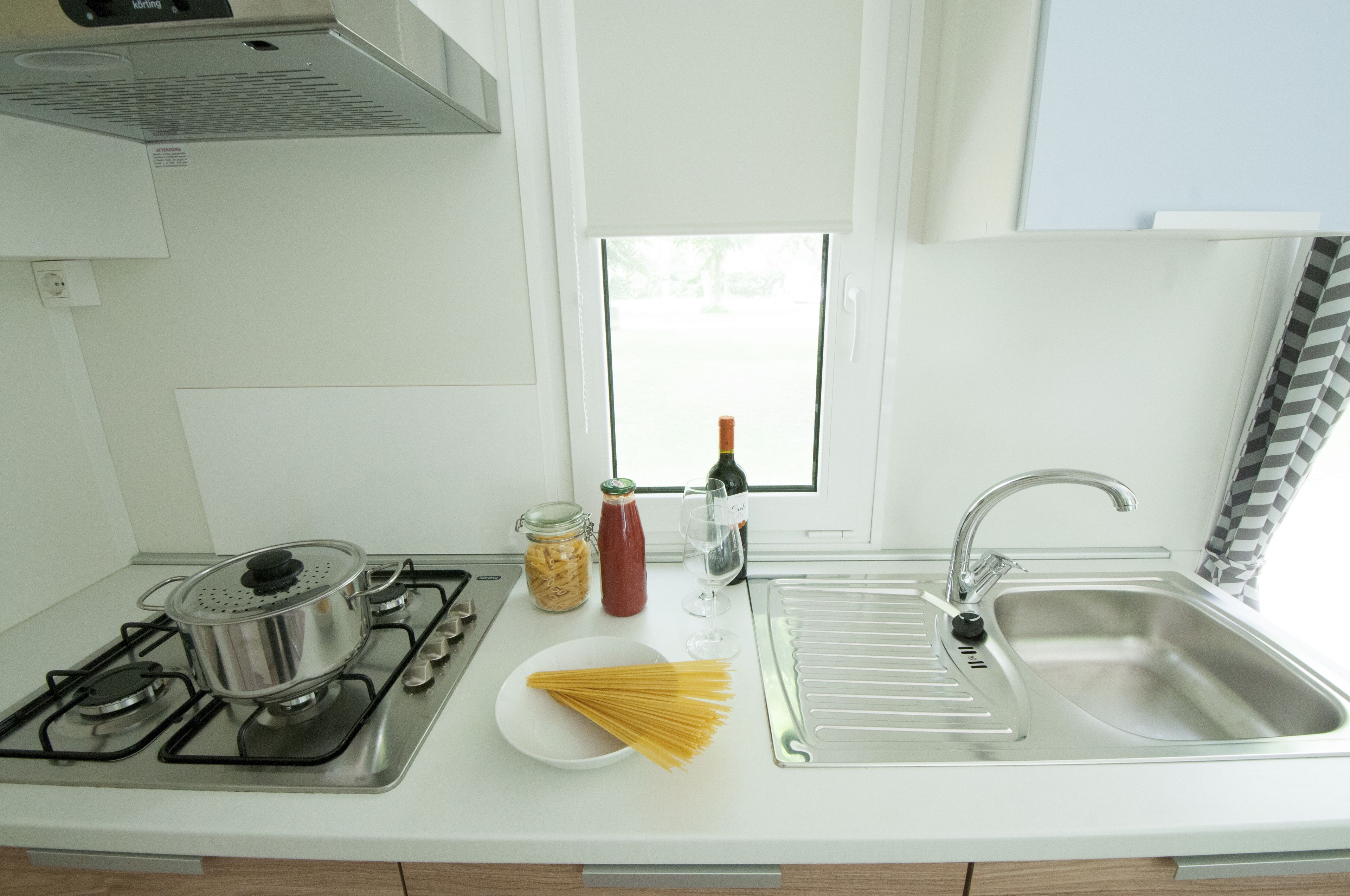 A kitchen with a stove, sink, and window.