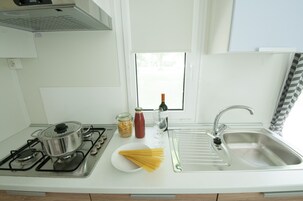 Una cucina con piano cottura, lavello e finestra.