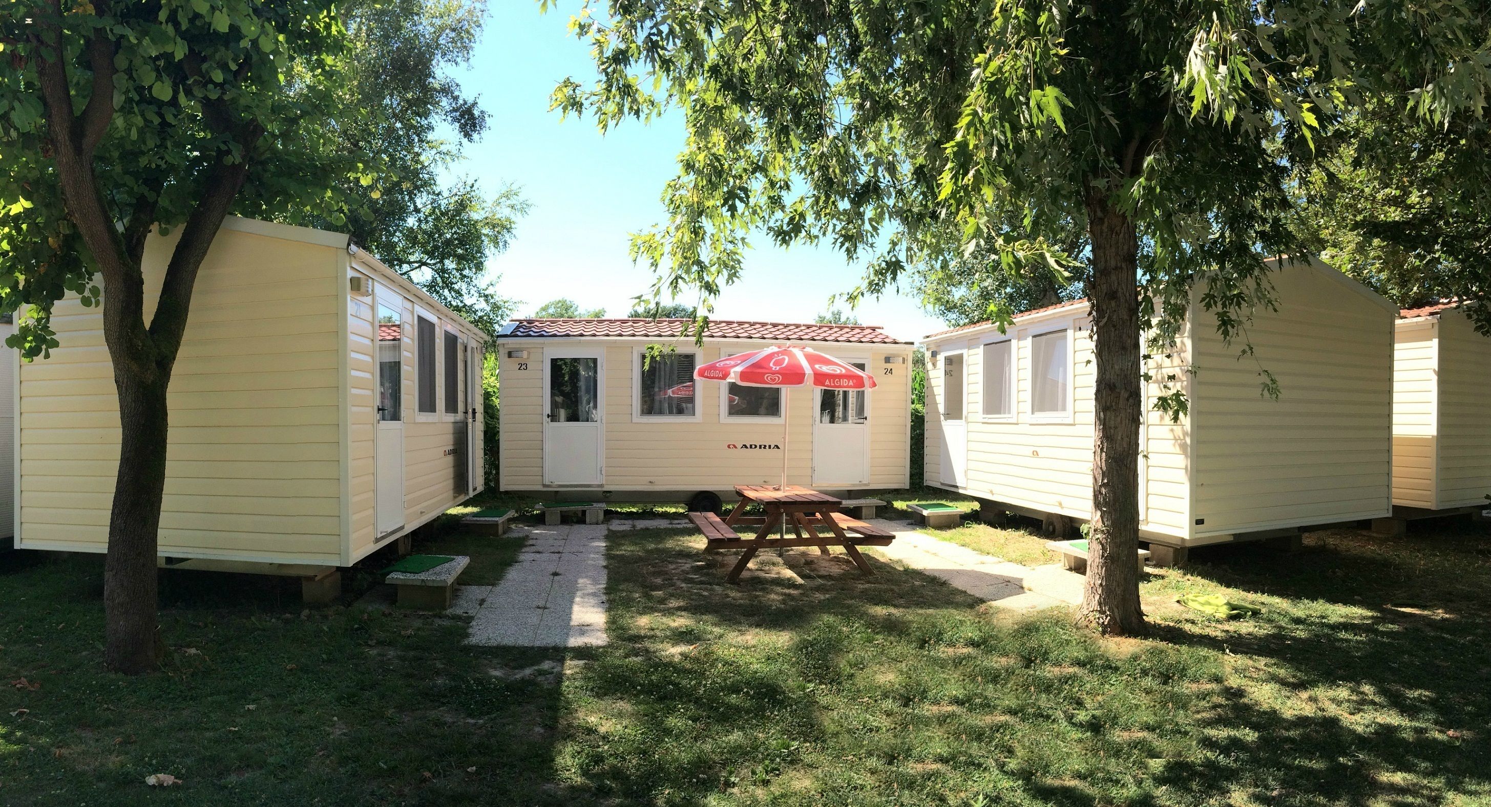 Un hilera de casas móviles con una mesa de picnic y una sombrilla en el centro.