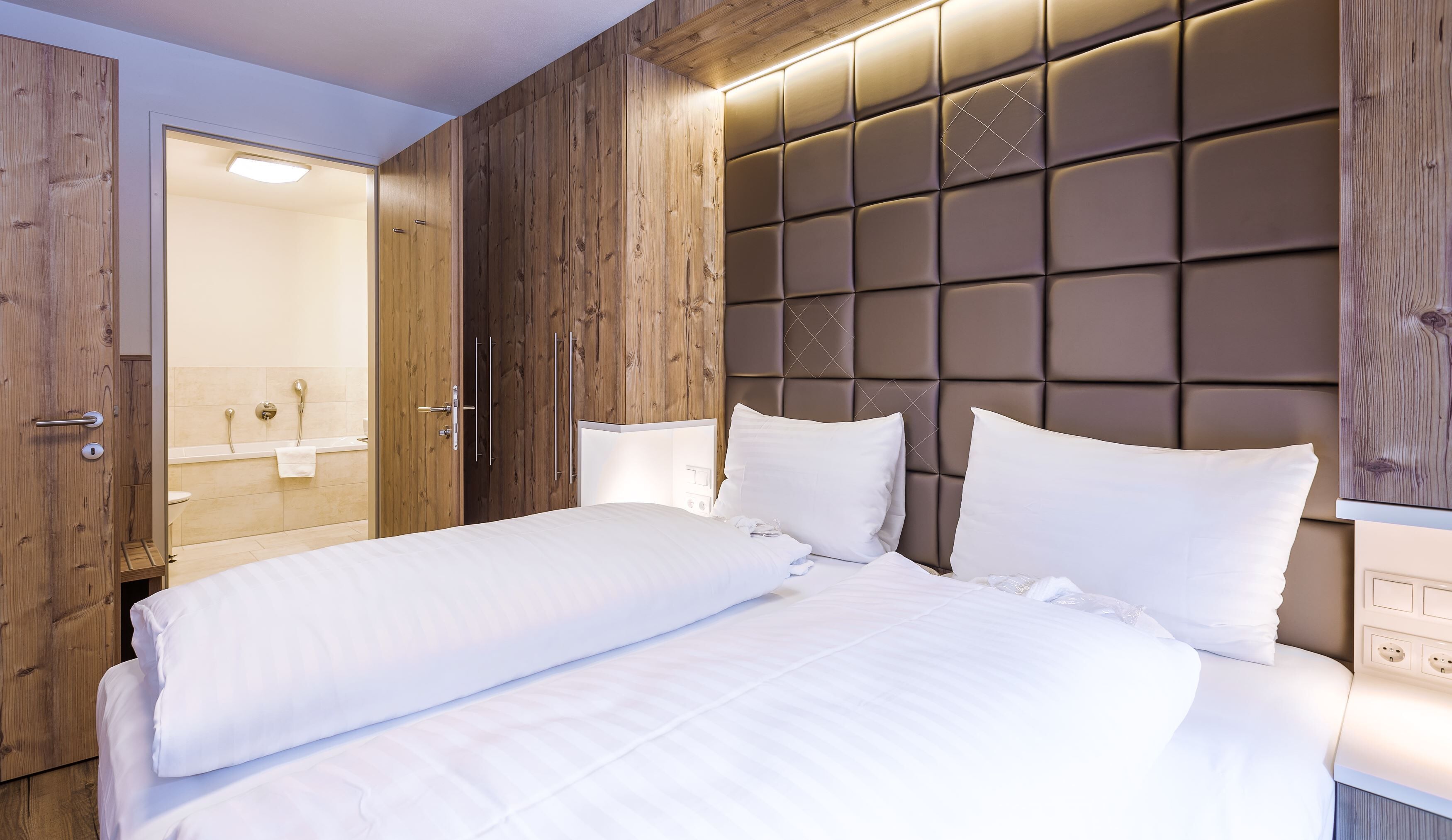 Une chambre à coucher moderne avec un grand lit, un lambris en bois et une tête de lit intégrée.