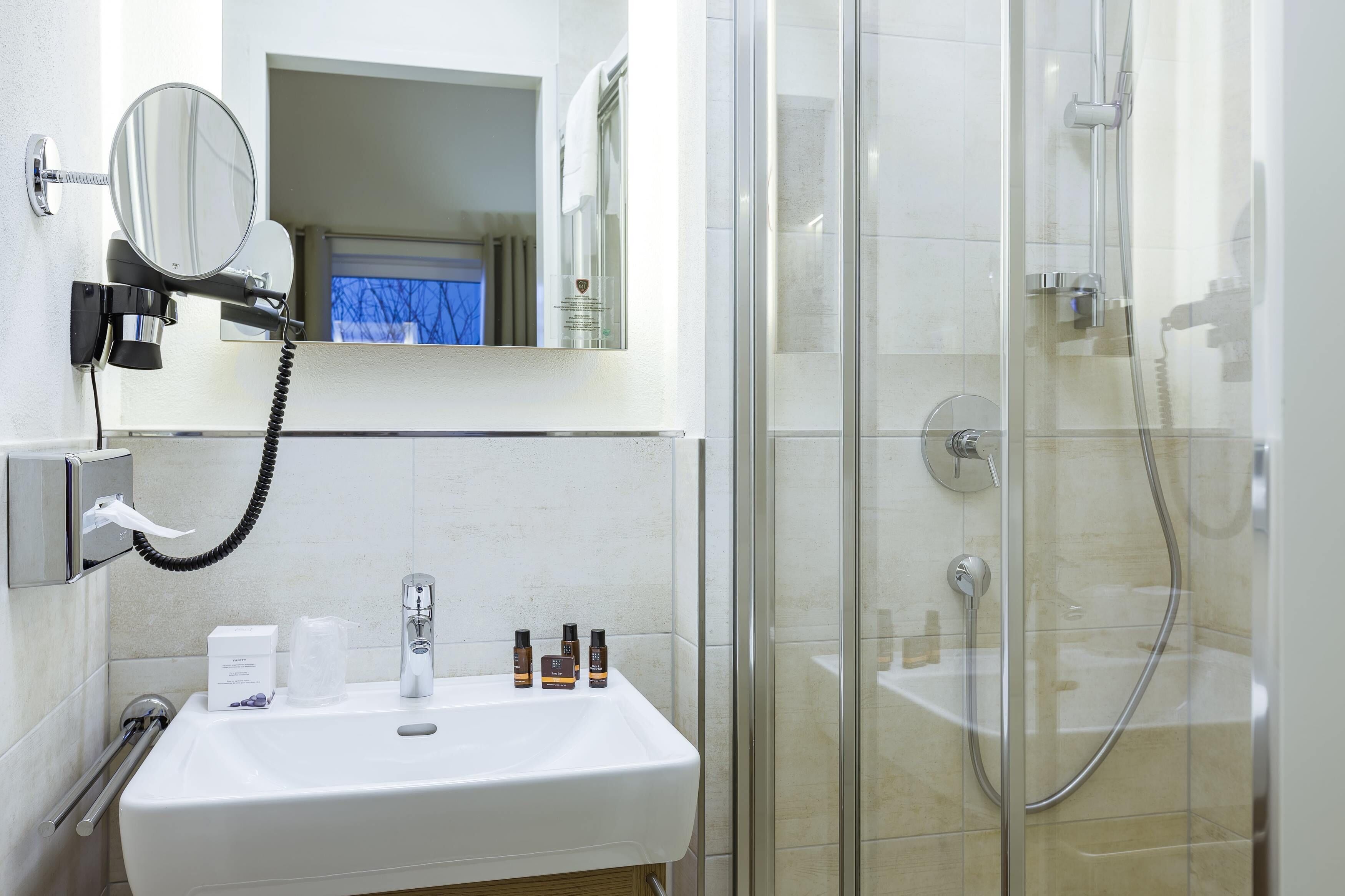 A bathroom with a white sink, a mirror, and a glass-enclosed shower.