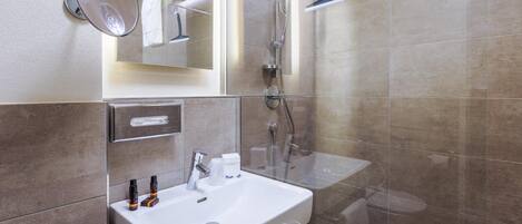 A modern bathroom with a white sink, mirror, and shower.