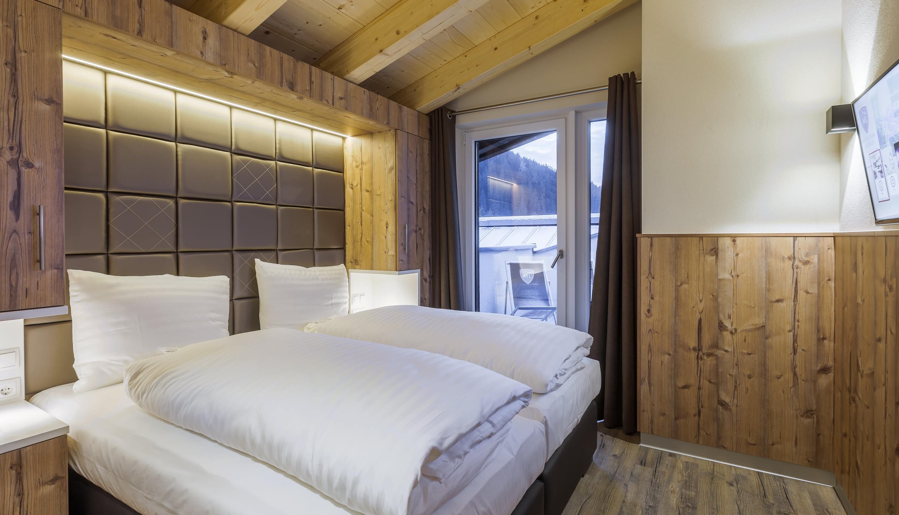 Un dormitorio con una cama grande, paneles de madera y vistas al exterior.