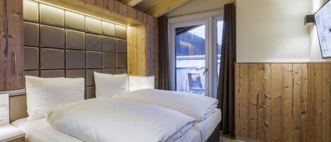 Un dormitorio con una cama grande, paneles de madera y vistas al exterior.