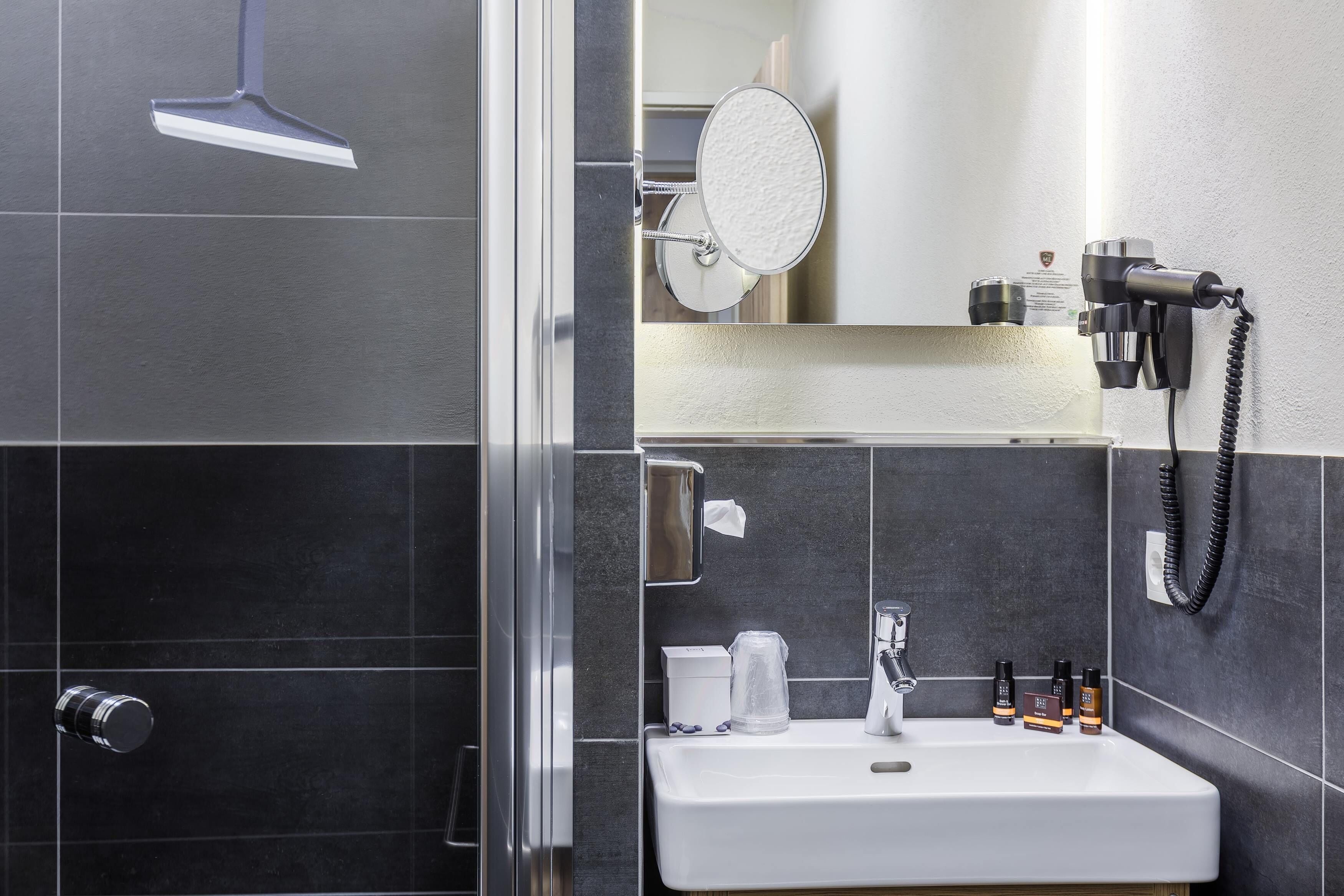 A modern bathroom with a shower, a sink, and a mirror.