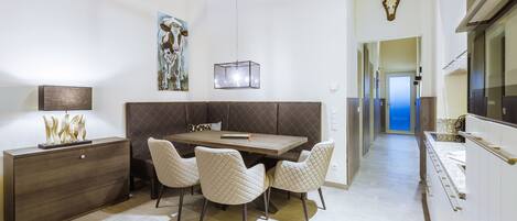 Un espace de salle à manger moderne avec une table en bois, des chaises rembourrées, un tableau et un crâne de cerf accroché au mur.