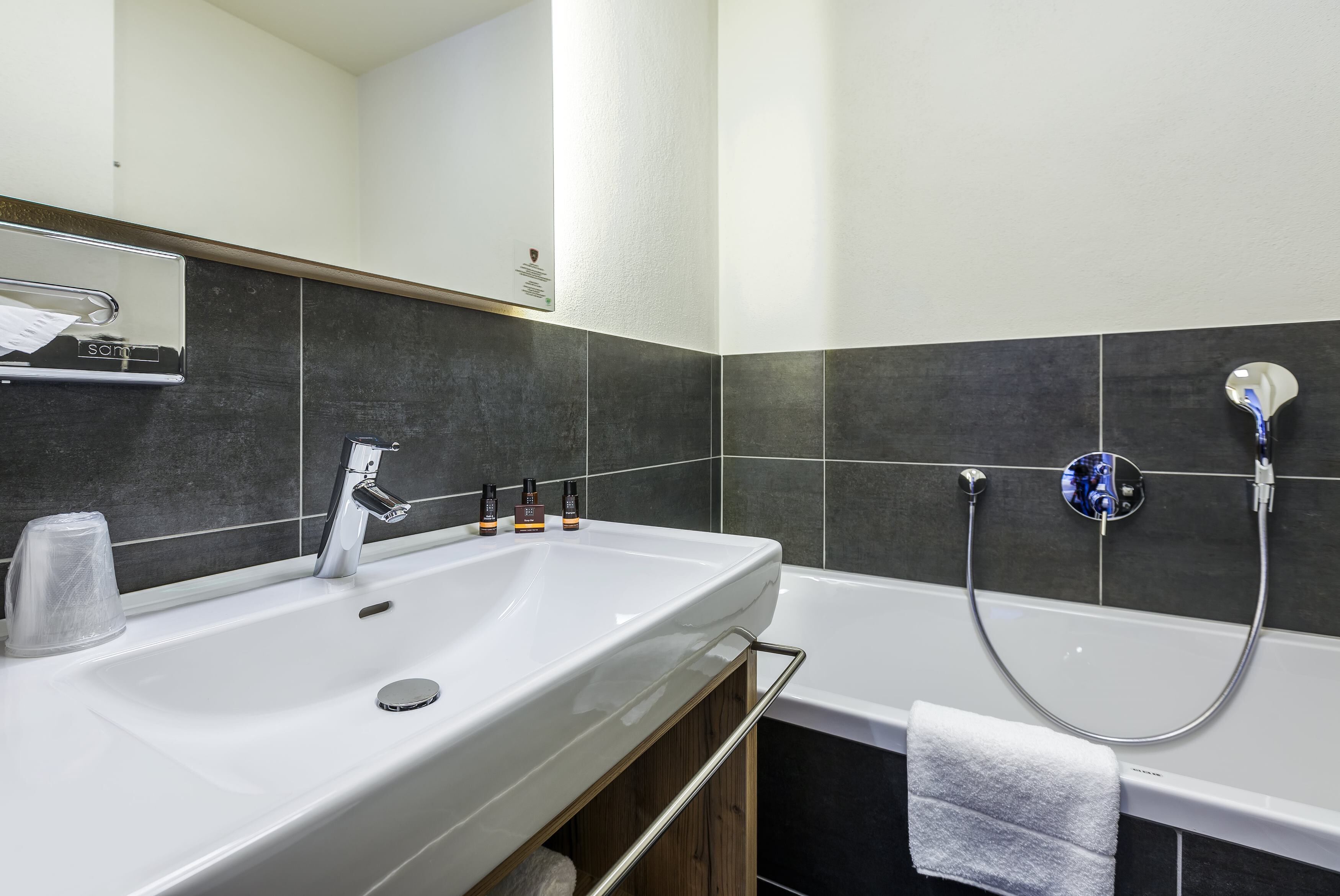 Un baño moderno con un lavamanos grande, una bañera y un cabezal de ducha.