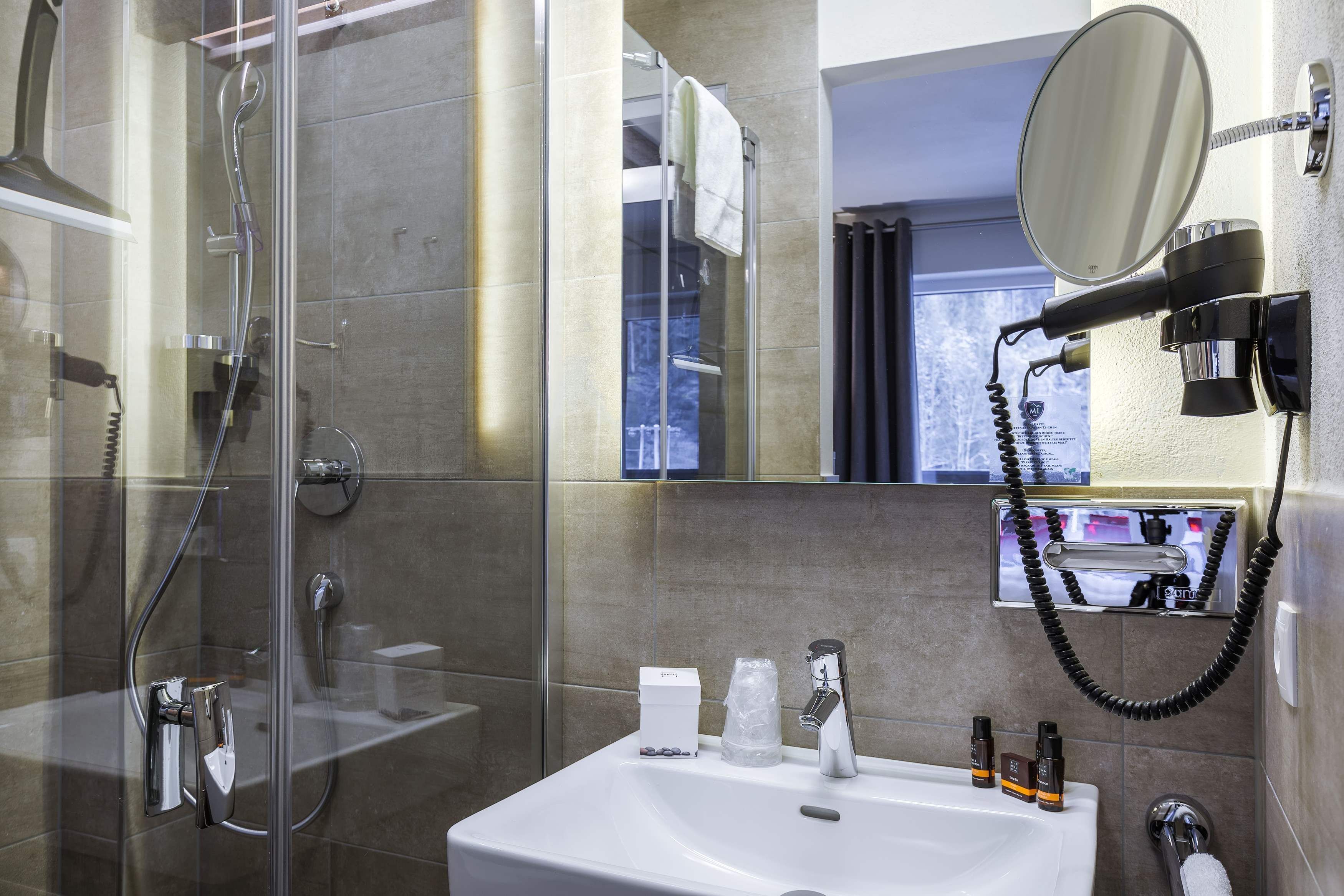 A modern bathroom with a glass-enclosed shower, a white sink, and a mounted mirror.