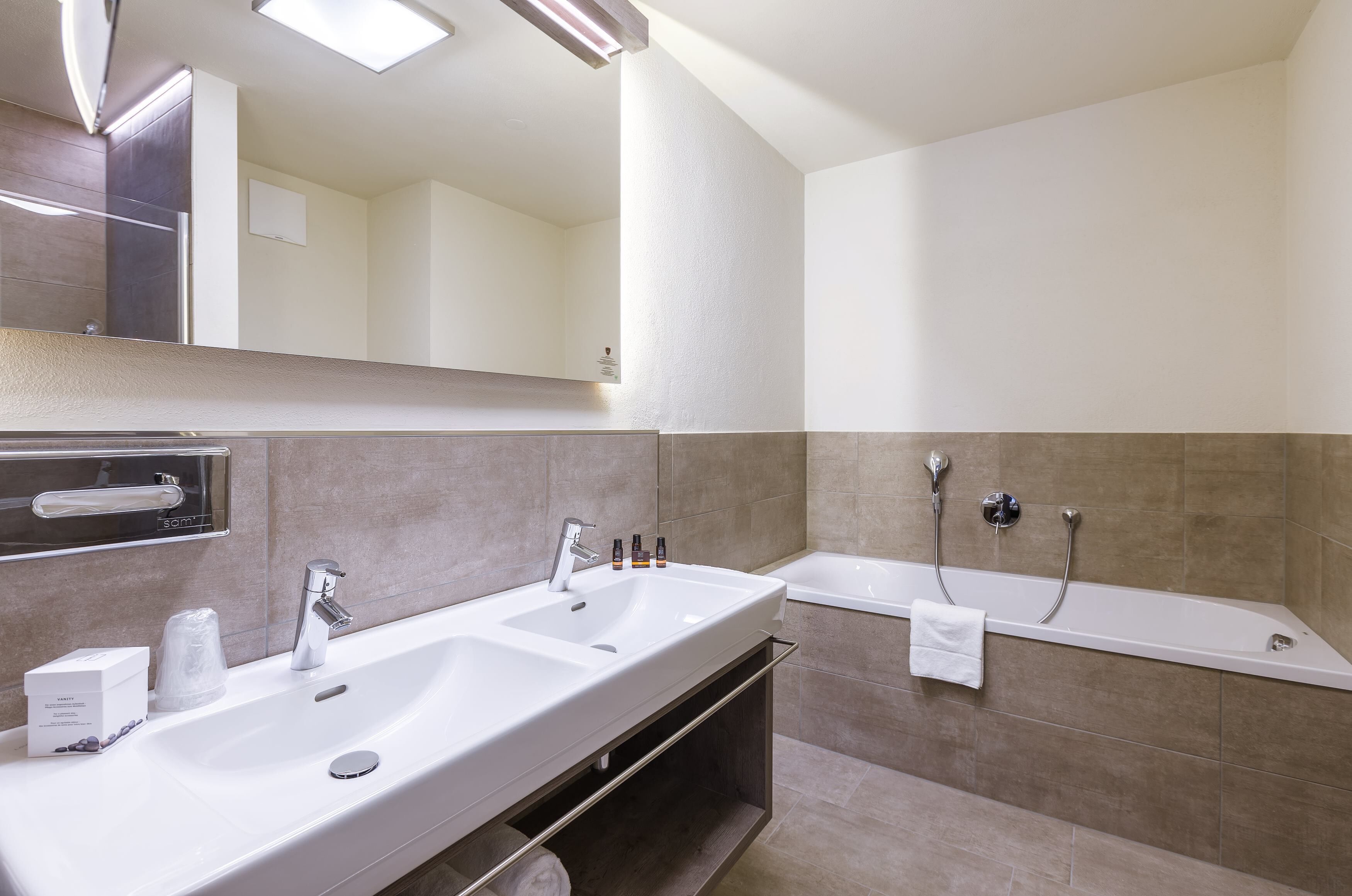 Uma casa de banho moderna com duas pias, um espelho grande e uma banheira.