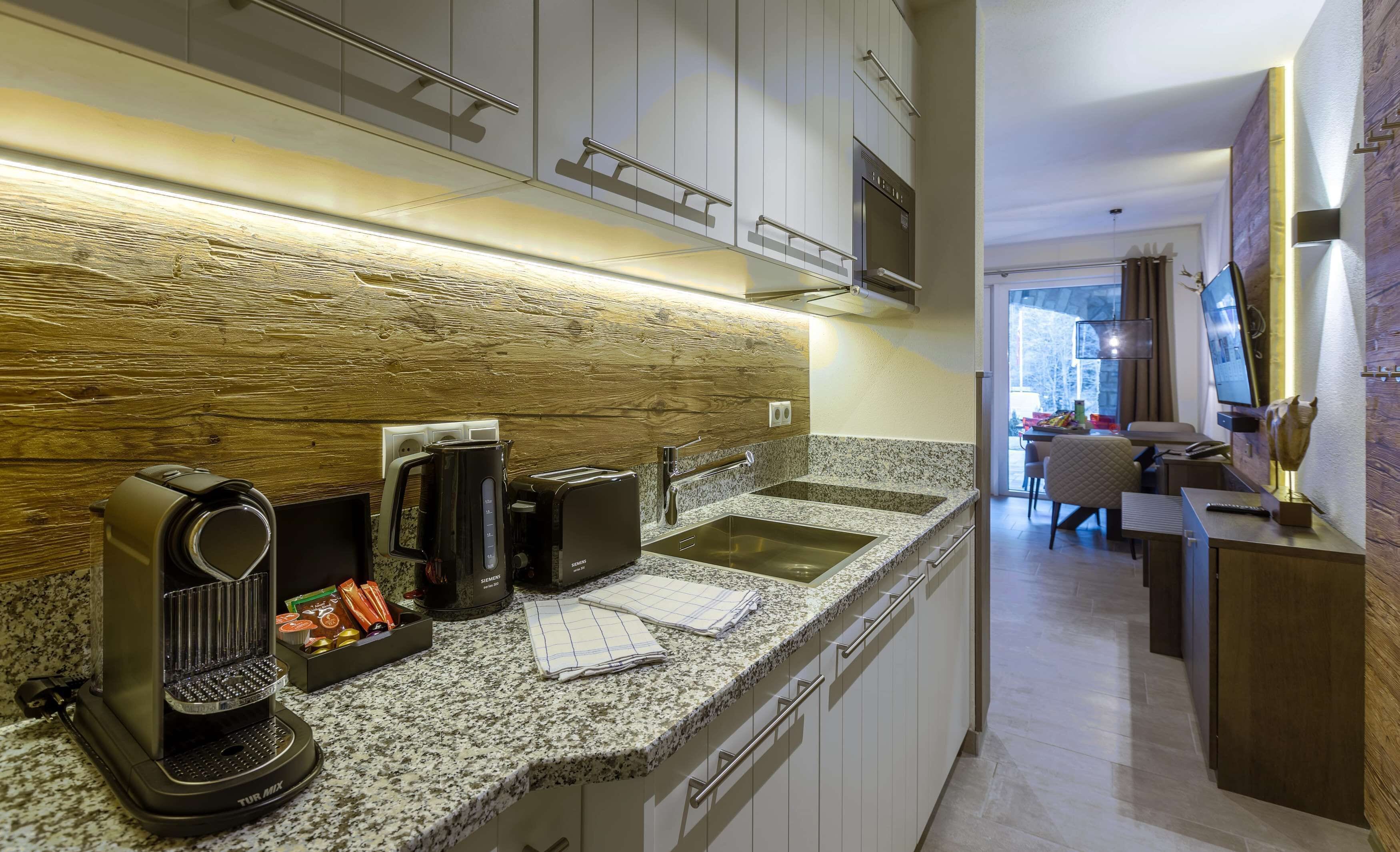 Cocina moderna con encimeras de granito, electrodomésticos de acero inoxidable y un salpicadero de madera.