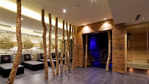 A modern lobby with birch tree-like columns, stone walls, and a wooden reception desk.