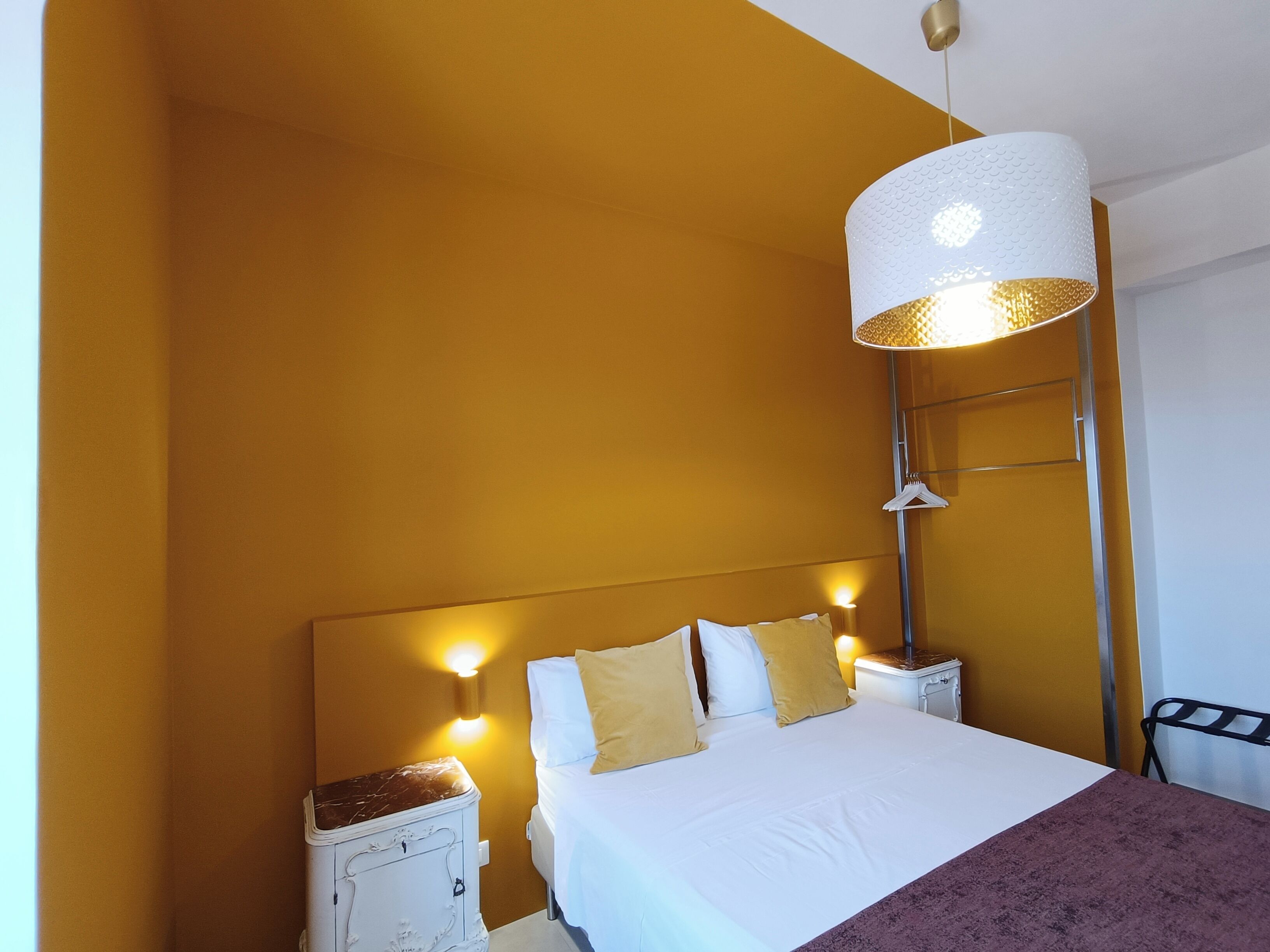 Ein Hotelzimmer mit Bett, Nachttischen, einer Lampe und einem Kleiderschrank.