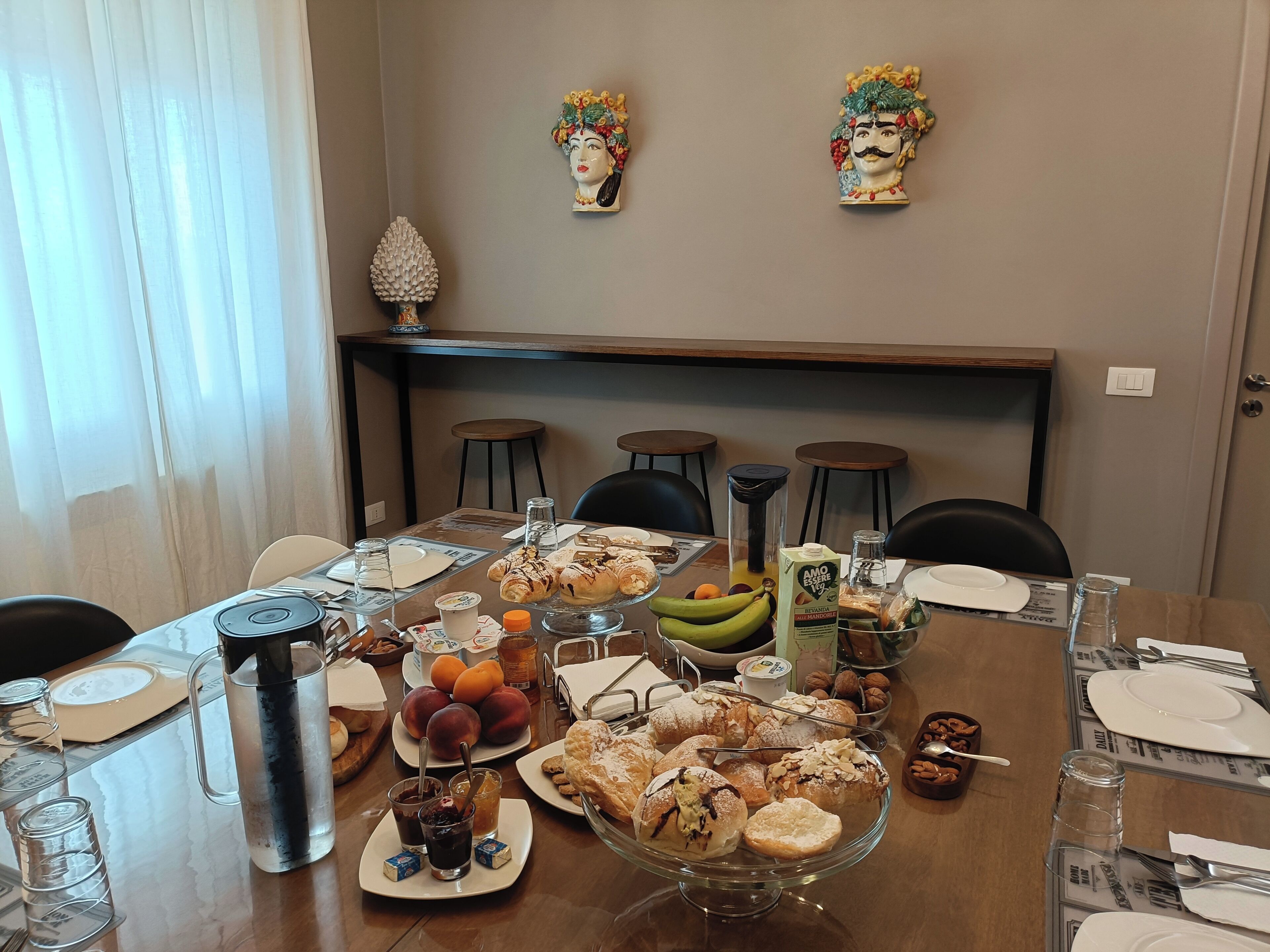 A dining table set with various pastries, fruits, and beverages, with chairs around it.