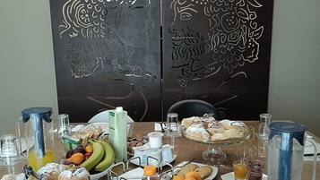 A breakfast buffet with various food items and beverages, a coffee maker, and a decorative panel with a crown design.
