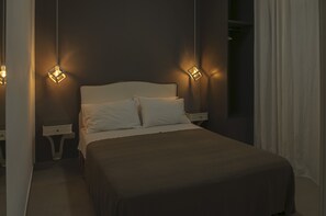 Un dormitori amb un llit, dues taules de nit i dues làmpades murals.