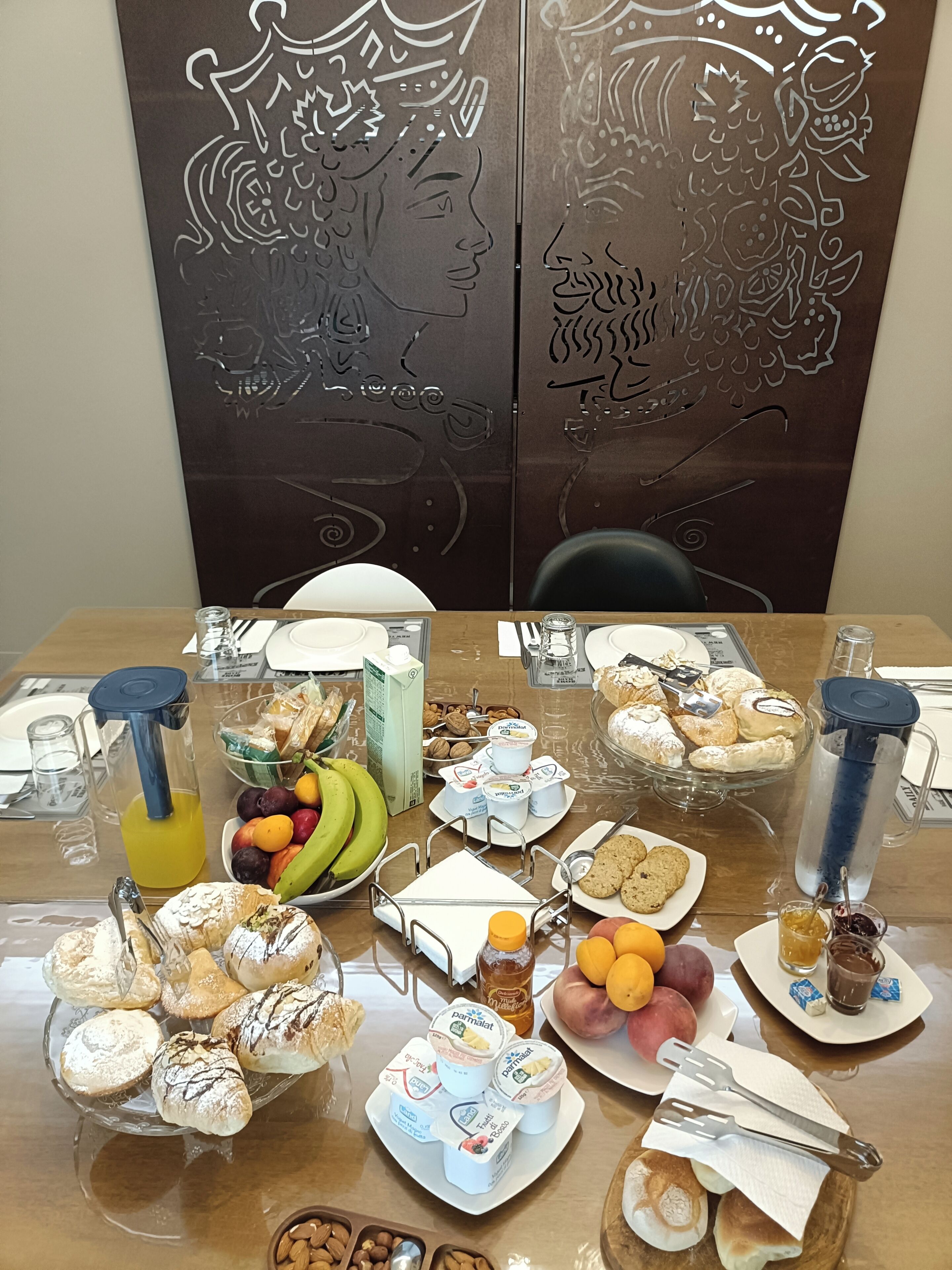 Een eettafel met diverse soorten eten, zoals gebak, fruit en toevoegingen.