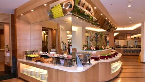 Eine moderne Hotelhalle mit einer zentralen Rezeption, einer Sitzecke und einem Buffet.