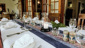 A long dining table set with white tablecloth, glassware, and a candle centerpiece. - York Lodge (Harare)