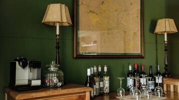 Una zona de bar con una máquina de café, botellas de vino y vasos sobre una encimera de madera.
