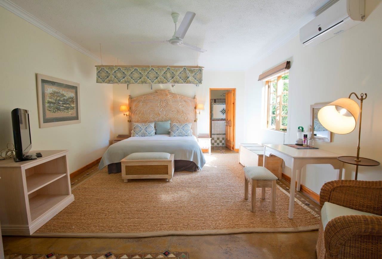 A bedroom with a bed, bedside tables, a desk, a chair, a lamp, and a ceiling fan.