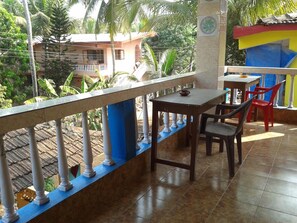 A balcony with a table and chairs, a tiled floor, and a view of buildings and trees.