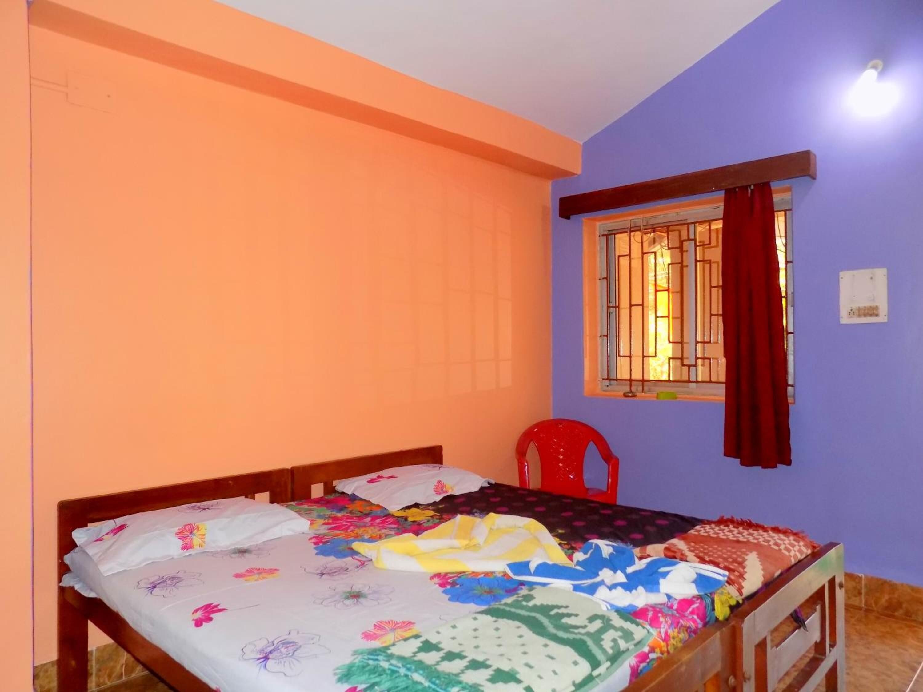 Un dormitorio con una cama, una ventana con rejas y una silla roja.