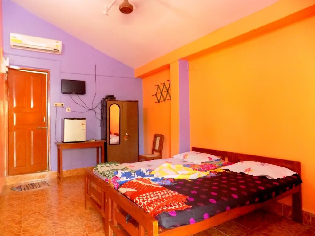 A bedroom with a bed, a television, a wardrobe, and an air conditioning unit.