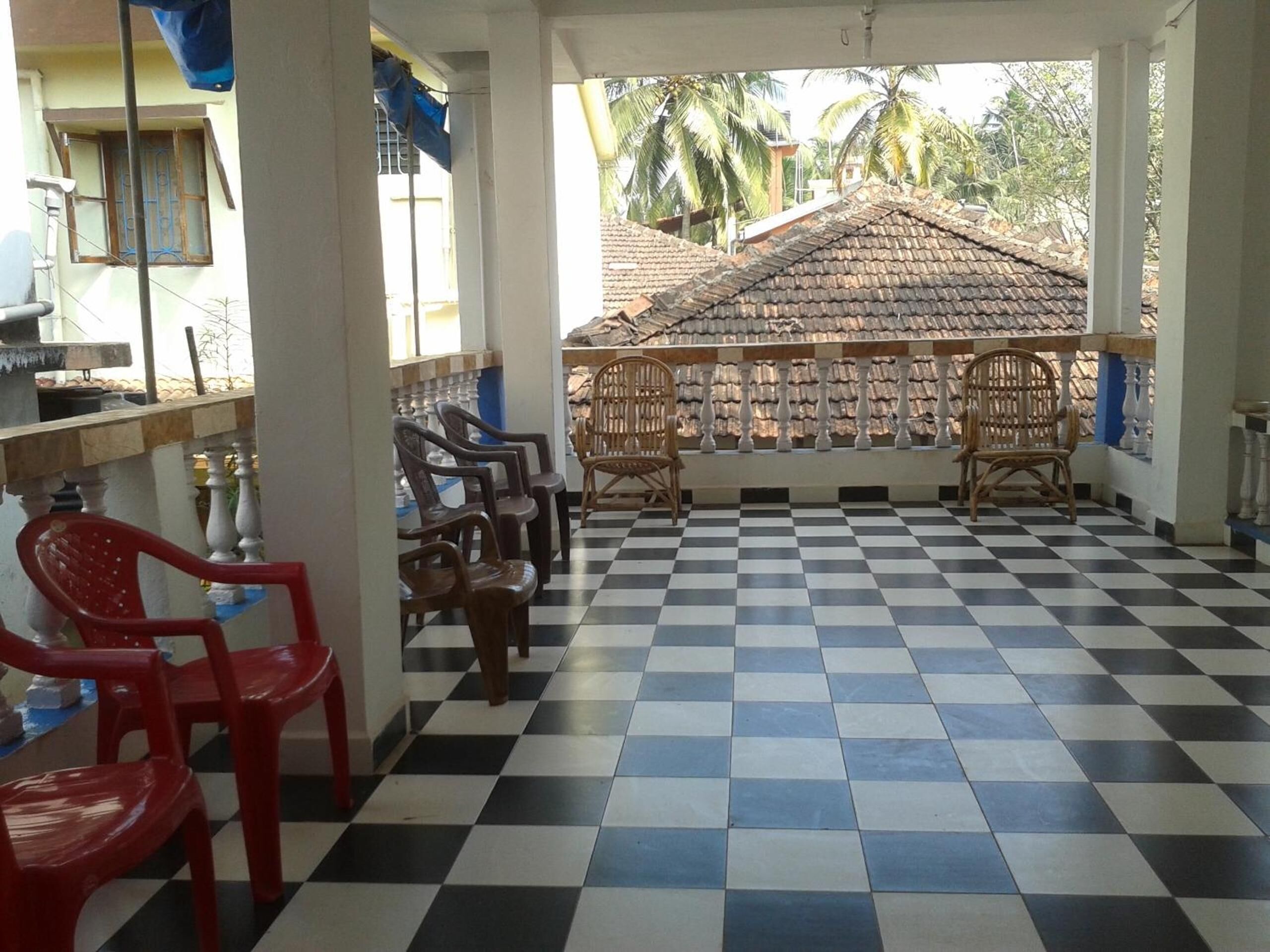 A checkered floor, a row of plastic chairs, and a view of a building with a tiled roof.