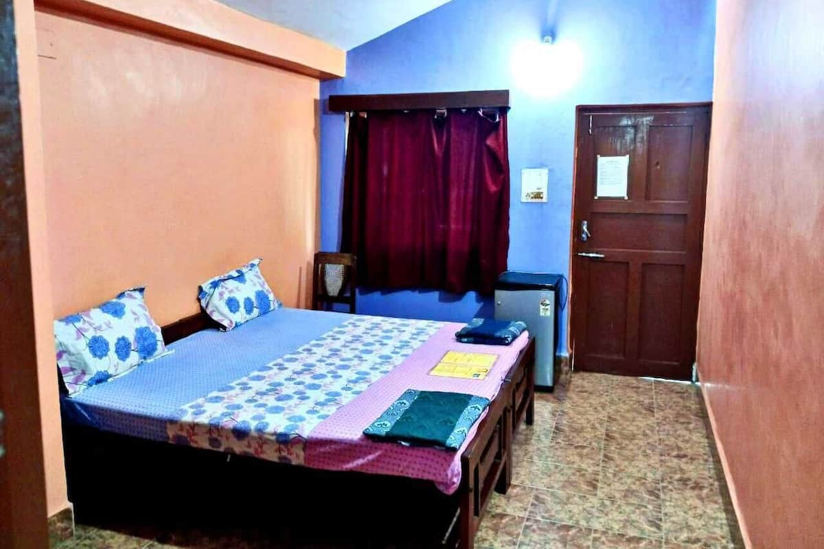 A bedroom with a bed, a desk, a chair, a wardrobe, and a door.