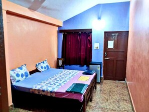 A bedroom with a bed, a desk, a chair, a wardrobe, and a door.