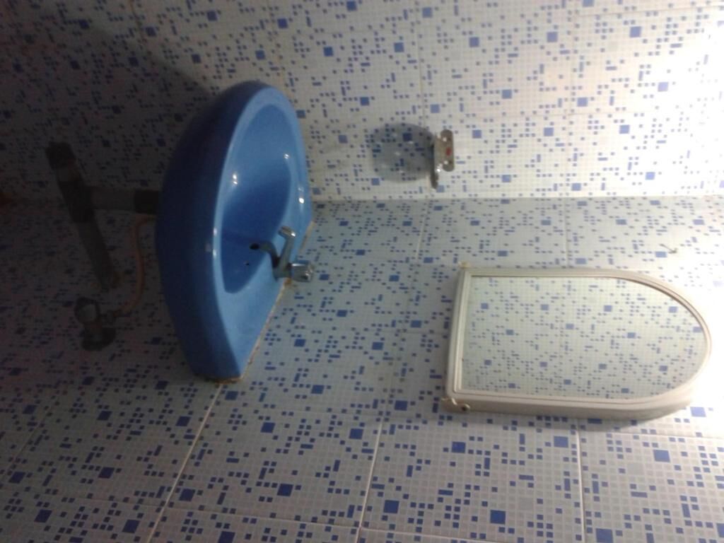 A bathroom with a blue sink, a toilet, and a mirror.