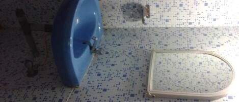 Un baño con un lavamanos azul, un inodoro y un espejo.