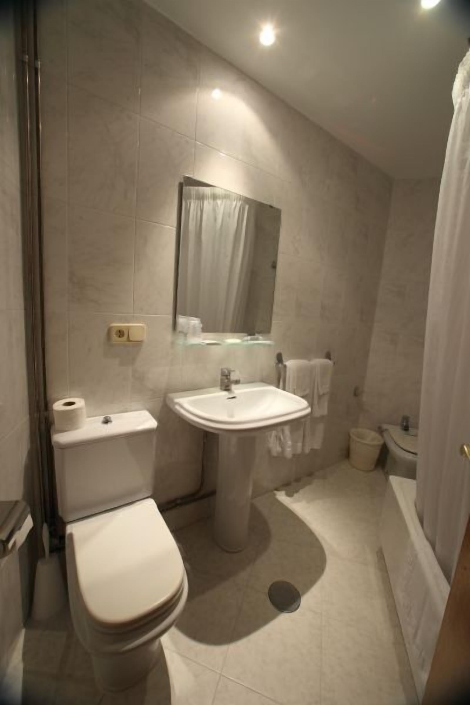 A modern bathroom with a toilet, sink, and shower.