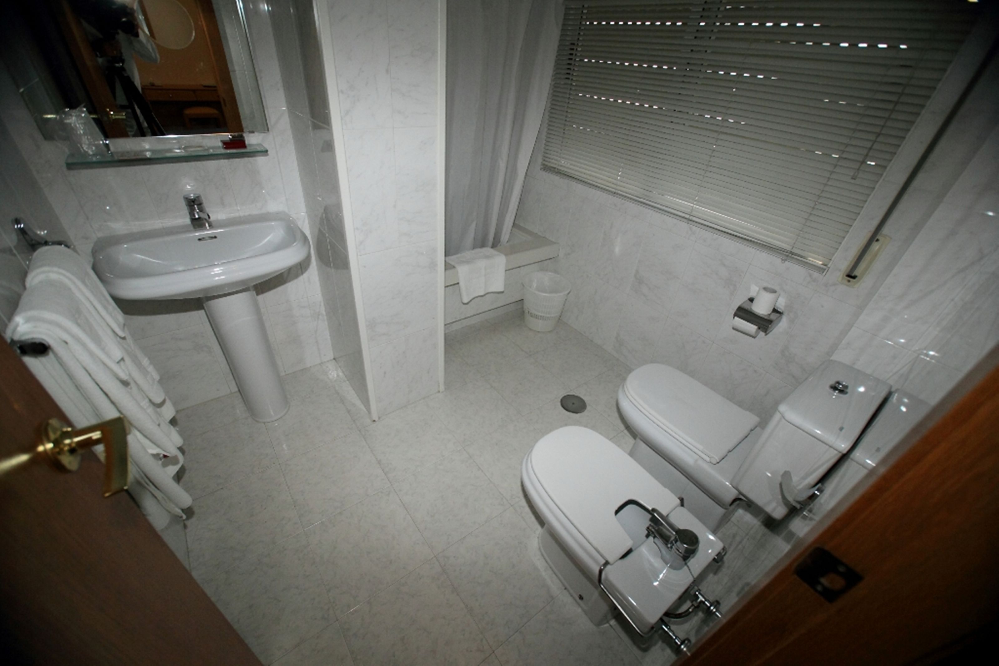 Une petite salle de bain propre, équipée d’un lavabo, de toilettes et d’une douche.