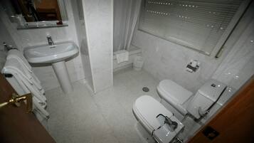 Une petite salle de bain propre, équipée d’un lavabo, de toilettes et d’une douche.