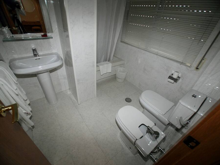 A small, clean bathroom with a sink, toilet, and shower.